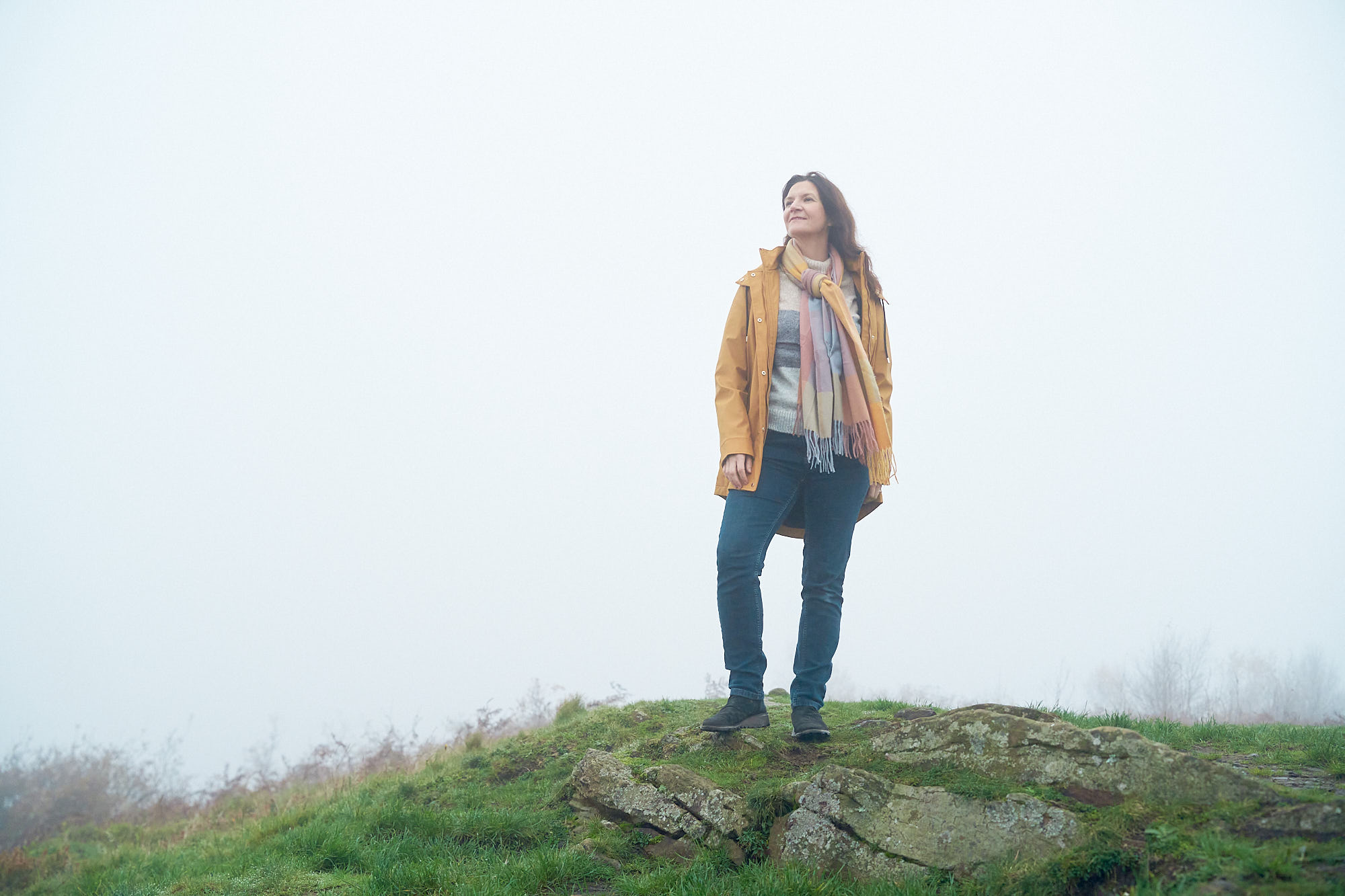 Woman stood on top of hill looking into distance smiling