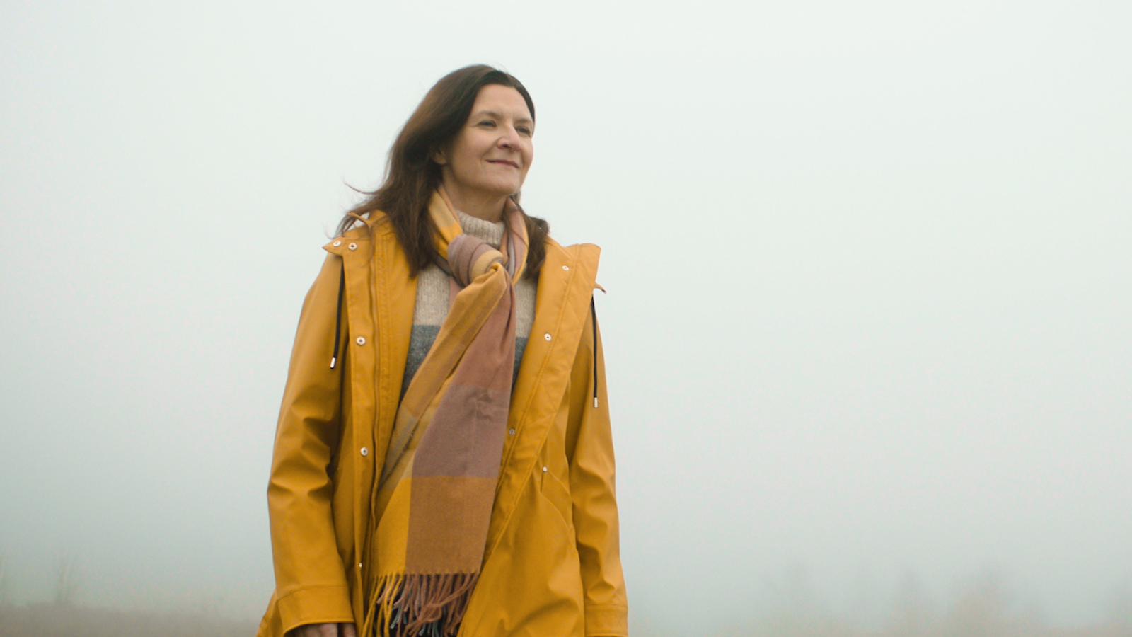 Woman outside looking into the distance smiling
